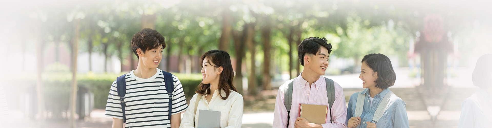 네 명의 학생들이 둘식 짝지어 서로를 마주보며 웃으며 교내를 걷는 사진